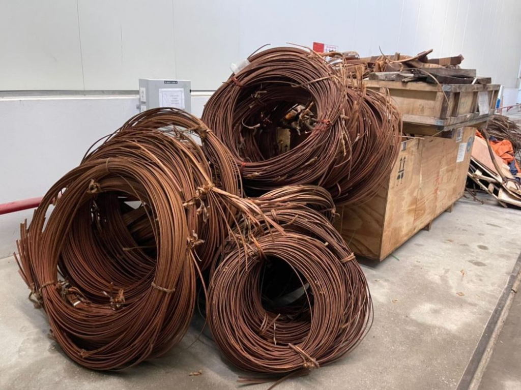 Coils of copper scrap metal stored in a warehouse setting